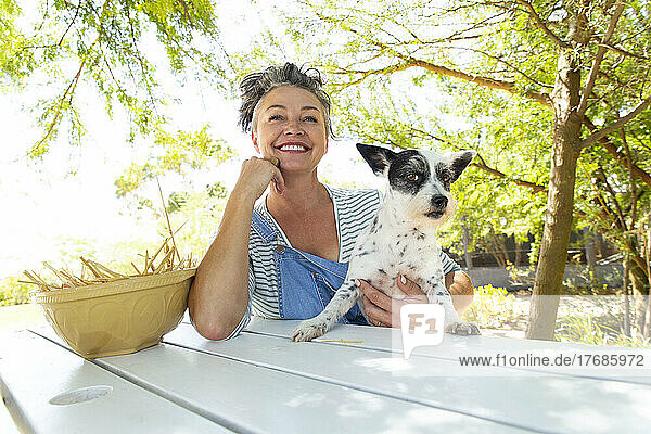 Woman sitting at table with dog in garden
