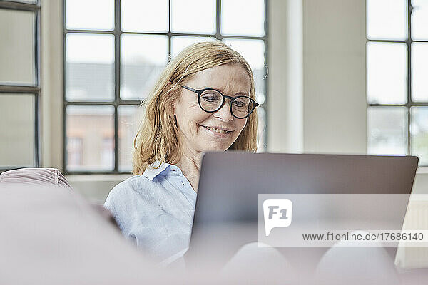 Happy freelancer wearing eyeglasses using laptop working at home
