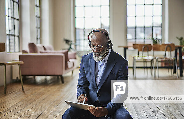 Businessman with headset using tablet PC with digitized pen at home