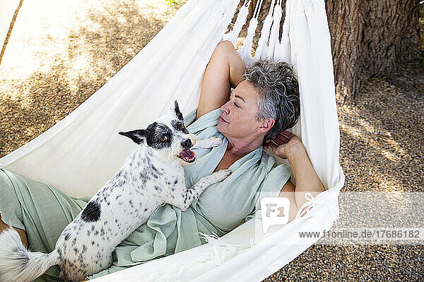 Woman with dog lying in hammock