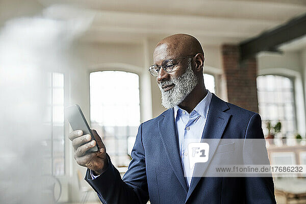 Mature businessman using smart phone at home