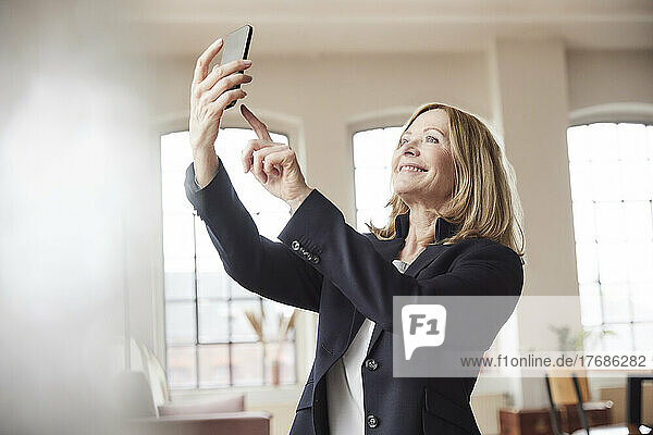Happy businesswoman taking selfie through smart phone at home