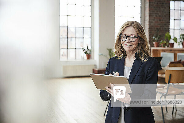 Smiling businesswoman using tablet PC standing in living room at home