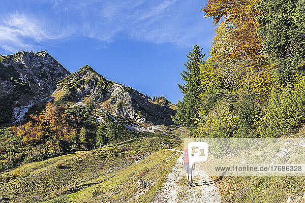 Germany  Bavaria  Female hiker following road to Geigelstein mountain