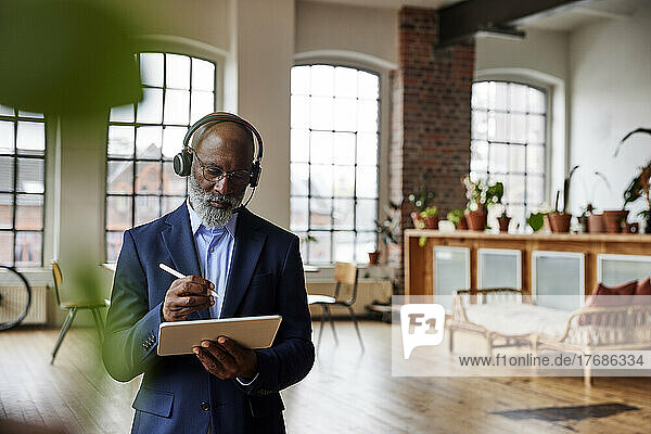Geschäftsmann mit Headset und digitalisiertem Stift auf Tablet-PC zu Hause