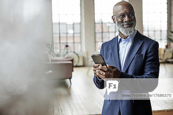Smiling businessman with mobile phone at home