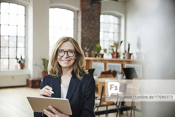 Lächelnde Geschäftsfrau mit Tablet-PC  die zu Hause im Wohnzimmer arbeitet