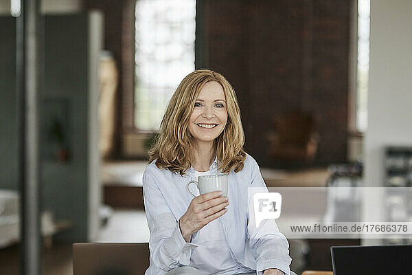 Glückliche Frau mit Kaffeetasse  die zu Hause sitzt