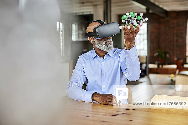 Scientist with VR goggles holding molecular structure at home