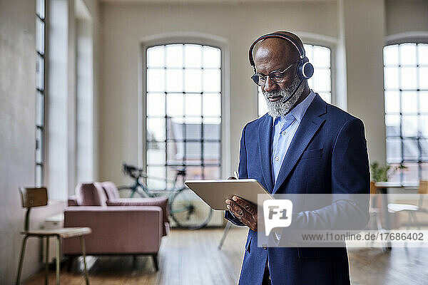 Businessman with headset working on tablet computer at home