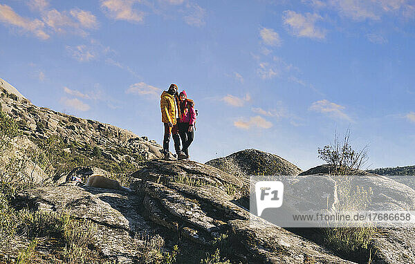 Couple standing together on rock on sunny day