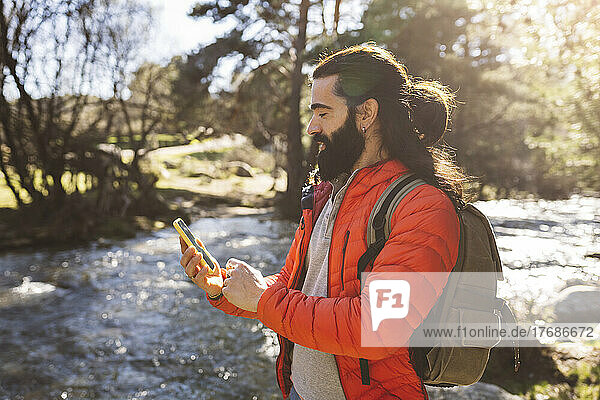 Bearded man using smart phone in forest