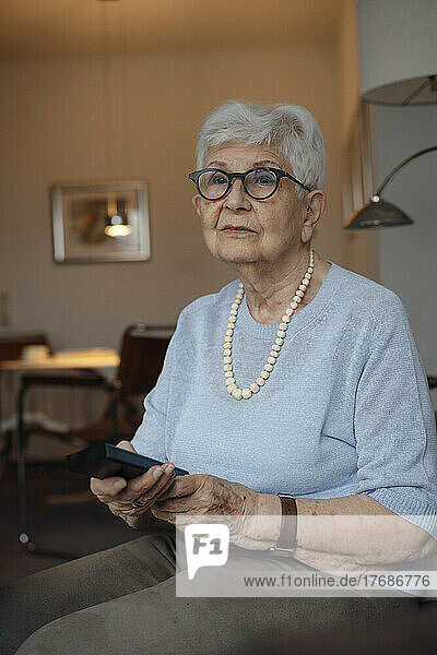Senior woman with remote control sitting at home
