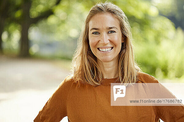Happy blond woman standing in park