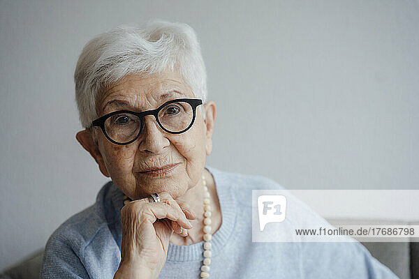 Smiling senior woman with hand on chin at home