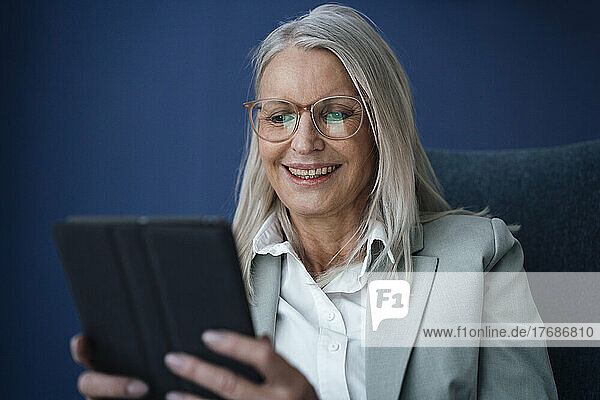 Glückliche Geschäftsfrau mit Brille und Tablet-PC