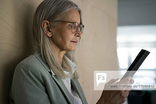 Ältere Geschäftsfrau arbeitet an einem Tablet-PC an der Wand