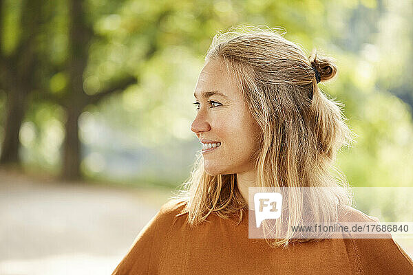 Smiling blond woman looking away in park