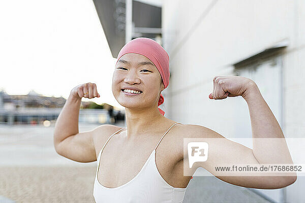Happy woman wearing pink bandana showing biceps