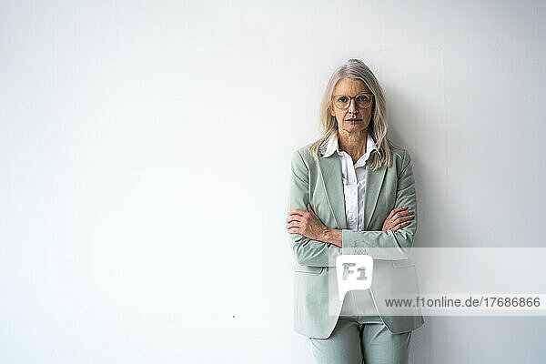 Confident businesswoman with arms crossed standing against white background