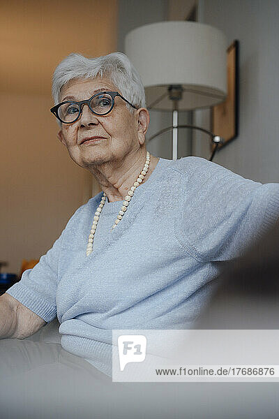 Ältere Frau mit Brille sitzt zu Hause