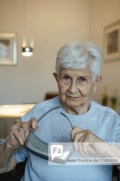 Smiling senior woman with virtual reality simulator sitting at home