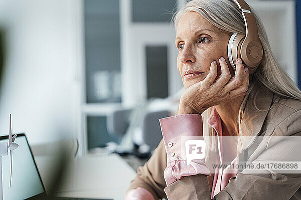 Businesswoman listening music through headphones at office