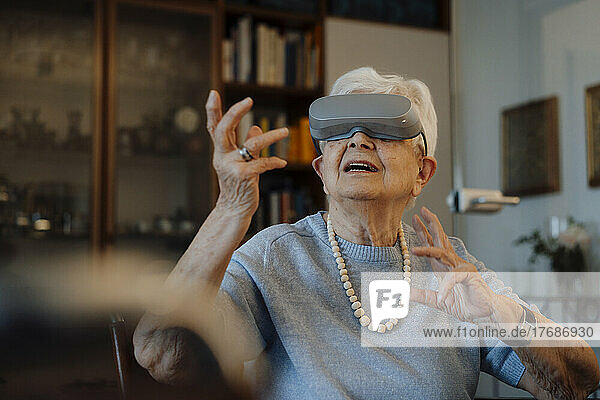 Ältere Frau mit Virtual-Reality-Simulator sitzt zu Hause