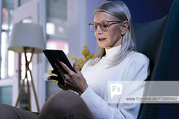 Senior woman with eyeglasses using tablet PC at home