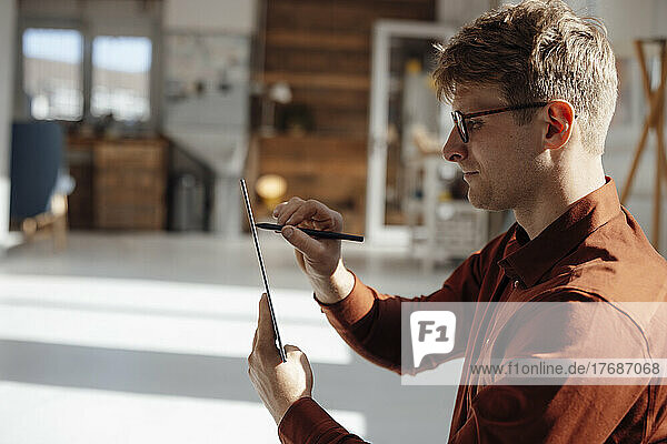 Businessman holding digitized pen using tablet PC in office