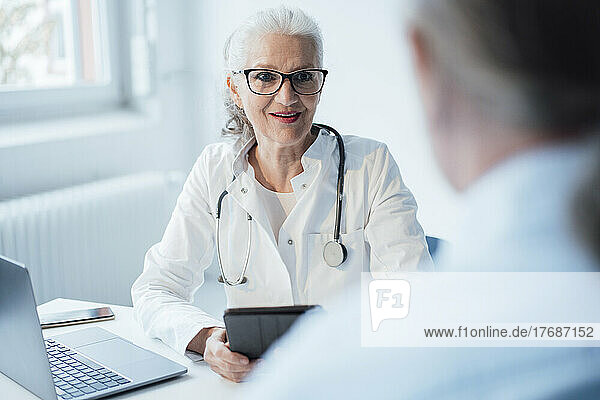 Senior doctor wearing eyeglasses discussing with patient
