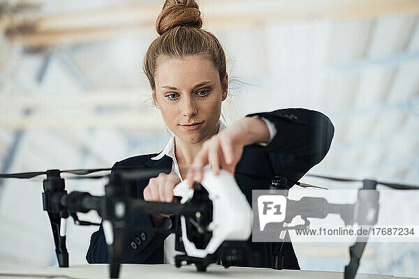 Young businesswoman testing drone at workshop