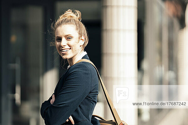 Smiling businesswoman outside office on sunny day
