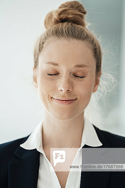 Smiling businesswoman with eyes closed at office