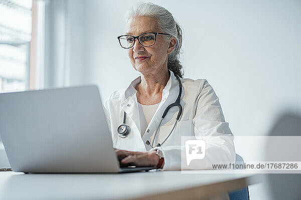 Doctor wearing eyeglasses using laptop at desk