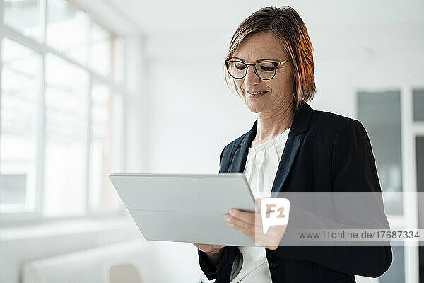 Happy businesswoman using tablet PC in office