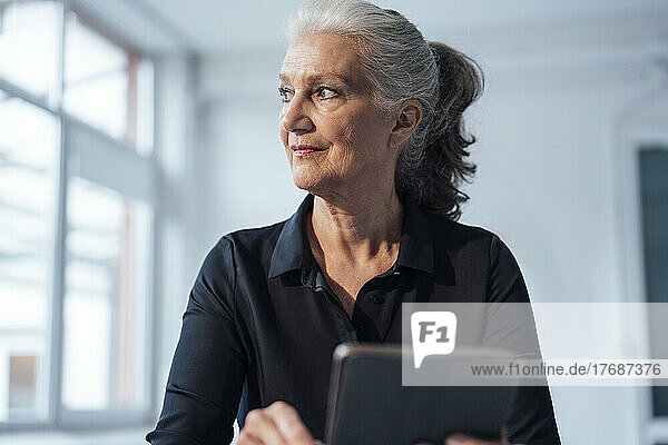 Senior businesswoman with tablet PC sitting in office