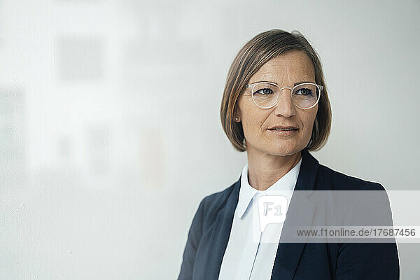 Businesswoman wearing eyeglasses in front of white wall