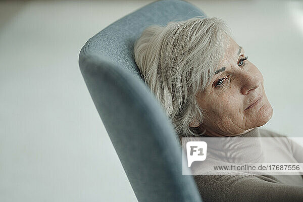 Thoughtful senior woman with gray hair sitting on chair