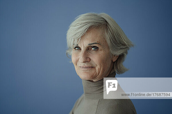 Smiling senior woman with gray hair against blue background