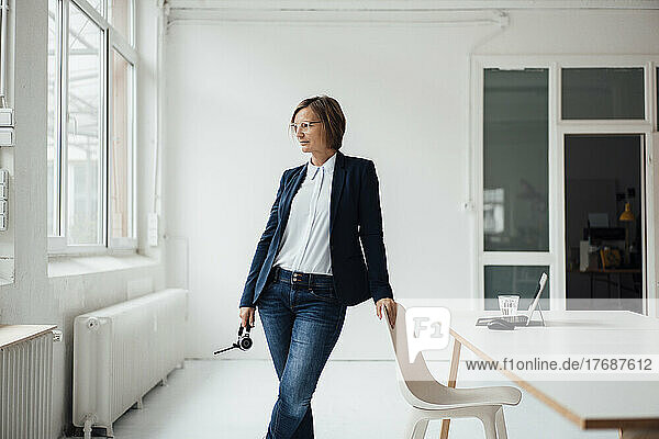Businesswoman wearing blazer standing by desk in office