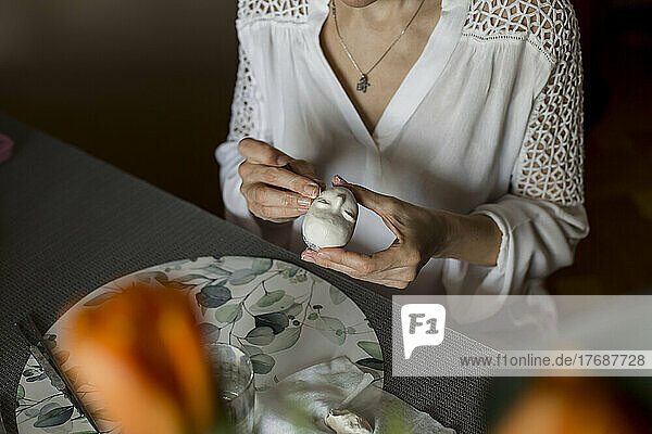 Mature woman sculpting dolls face sitting at home