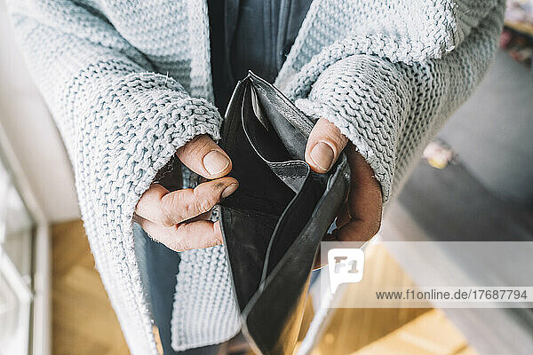 Hands of man wrapped in blanket holding empty wallet