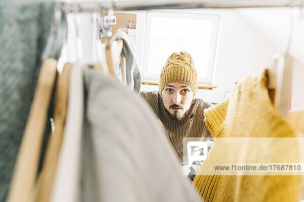 Young man searching for warm clothes in wardrobe