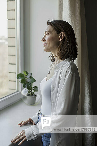 Happy woman standing in front of window at home