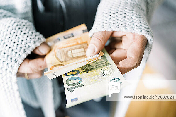 Hände eines Mannes  der in eine Decke gehüllt ist und Euro-Banknoten hält