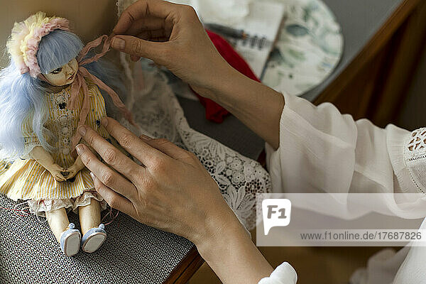 Hände einer Frau  die zu Hause eine handgemachte Puppe dekoriert