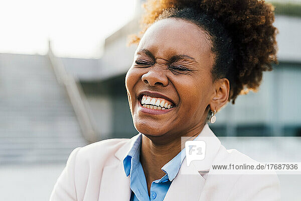 Afro businesswoman laughing with eyes closed
