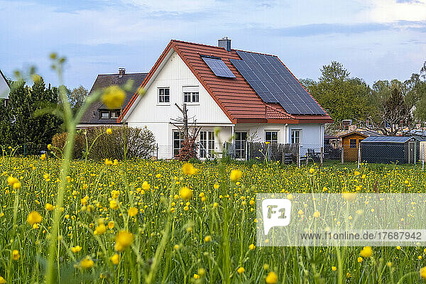 Solar panels on rooftop of house by meadow