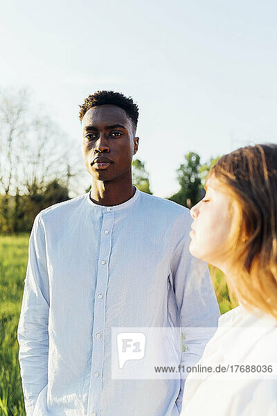 Young man standing by girlfriend in nature on sunny day